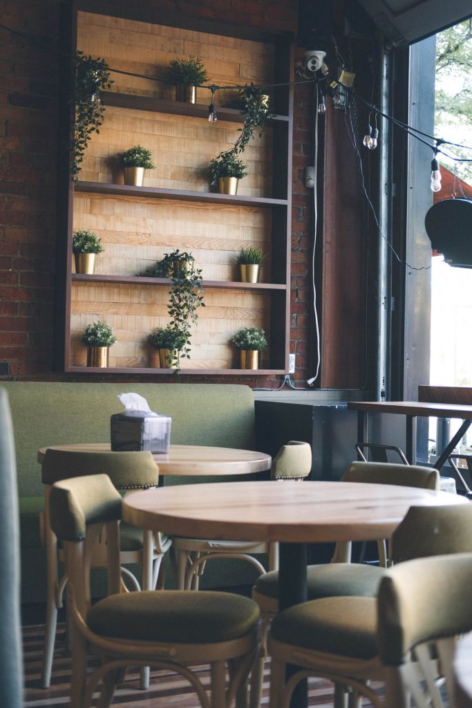 Cafe dining corner with banquette seating, timber tables and open shelving.